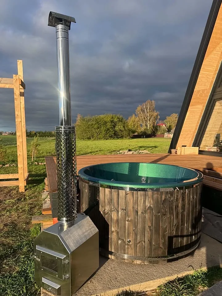 Dark cladding tub with emerald interior and external stove at sunset